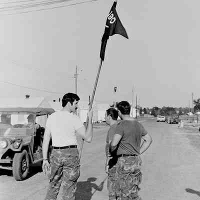 Soldier holding a guidon in camp area