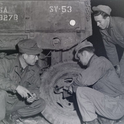 Three soldiers changing a tire on a truck
