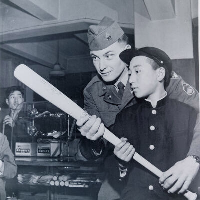 Soldier teaching a young Japanese boy how to hold a baseball bat