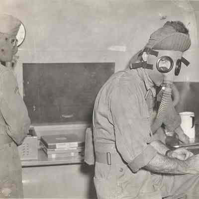Soldiers developing photos while wearing gas masks