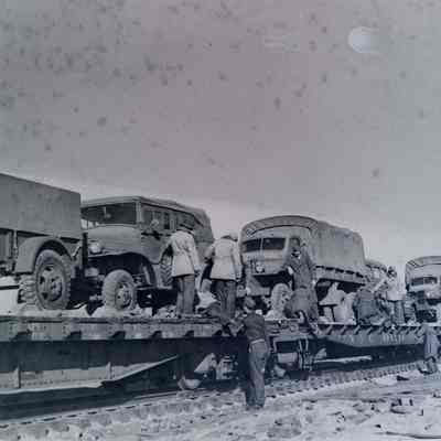 Soldiers loading trucks on train cars