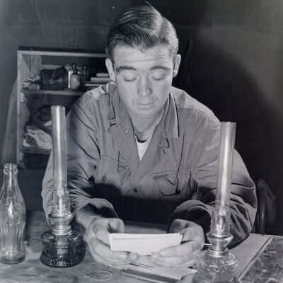 Soldier reading by oil lamps