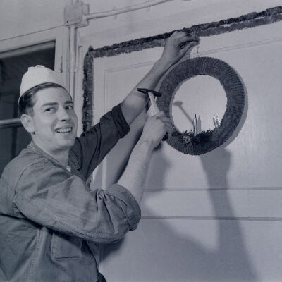 A cook hanging Christmas decorations in a mess hall