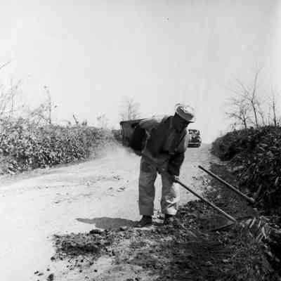 Japanese man clearing roadside ditch