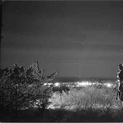 Night shot of a soldier on a hill with Camp Barkeley in the background