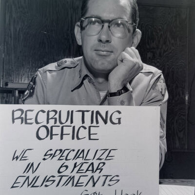 Recruiter sitting at desk behind sign
