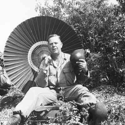 Soldier with parasol and fanning himself with his helmet