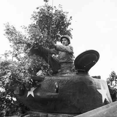 Soldier adjusting camouflage on a tank