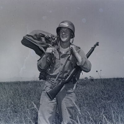 Soldier with weapon and parachute in a field
