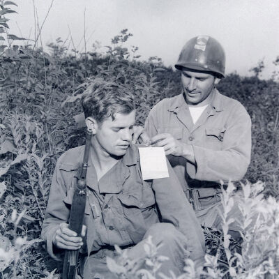 Soldier tying a tag onto a soldier's shoulder