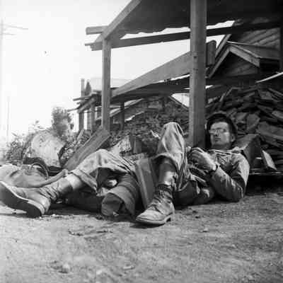 Soldier napping next to wood pile