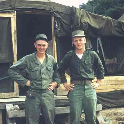 Two soldiers posing outside of a tent