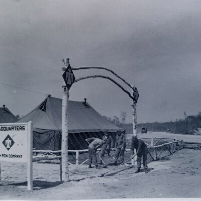 Soldier work party in front of tents with sign for HQ 45th Recon Company