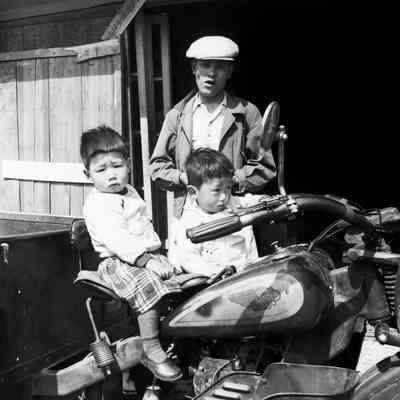 Japanese man with two children seated on a motorcycle