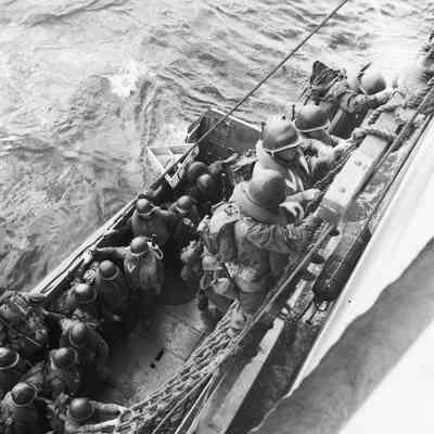 Soldiers climbing down nets into landing craft