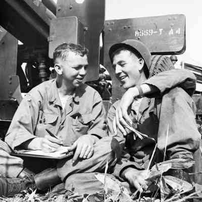 Two soldiers sitting next to an artillery piece