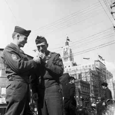 Soldiers lighting a cigarette in the street