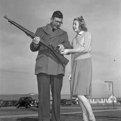 Soldier instructing a girl about a rifle