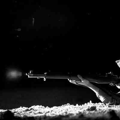 Night photo of a soldier firing his rifle