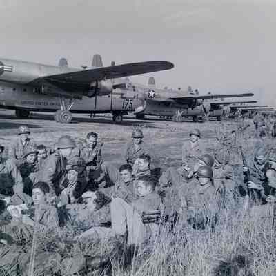 Soldiers relaxing at the edge of a flight line with transport aircraft in background