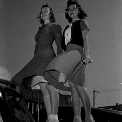 Girls standing on the hood of a car