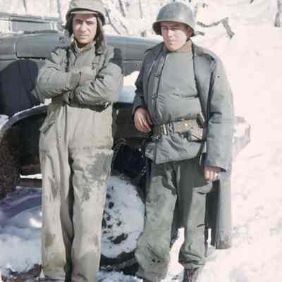 Two soldiers in front of a truck in the snow