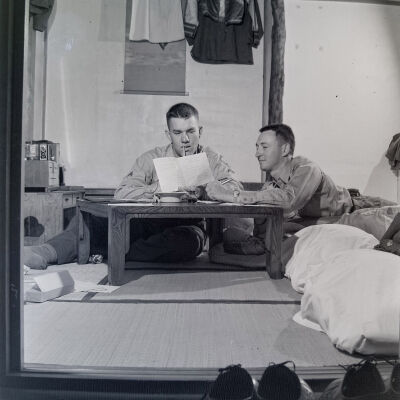 Two soldiers writing letters in a Japanese hotel room