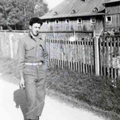 Soldier posing in front of wooden barn