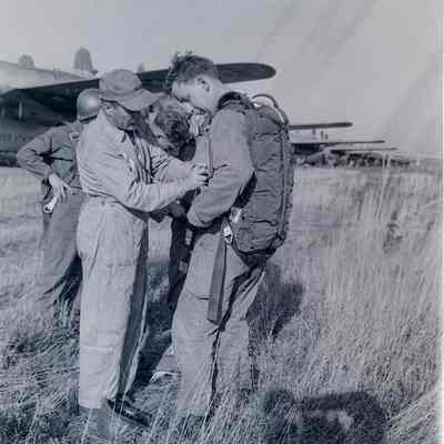 Instructor helping a paratrooper with his gear