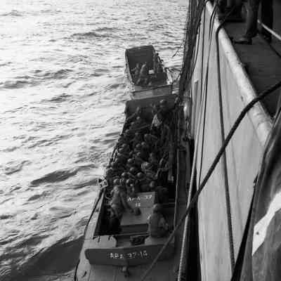 Soldiers climbing down nets into landing craft