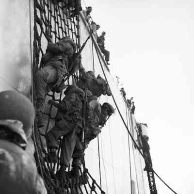 Soldiers climbing down nets into landing craft