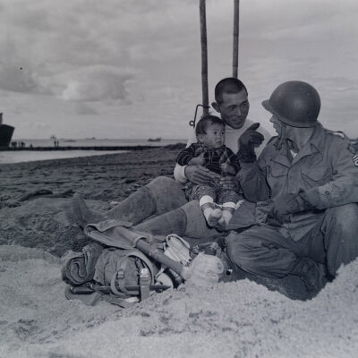 Soldier on beach talking with a Japanese father and child
