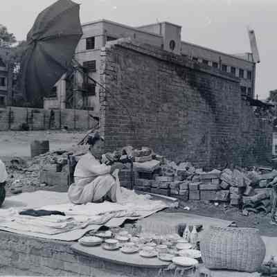Woman selling cups and dishes amid ruins