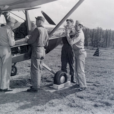 Soldiers loading a man on stretcher into a light observation aircraft