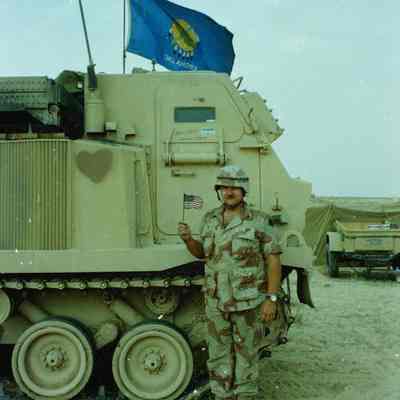 Soldier with American flag standing in front of MLRS with Oklahoma flag