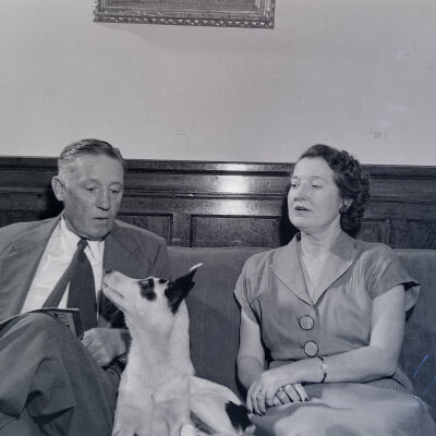 Civilian couple seated on couch with a dog