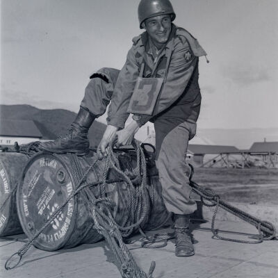 Soldier tying down a barrel of motor fuel
