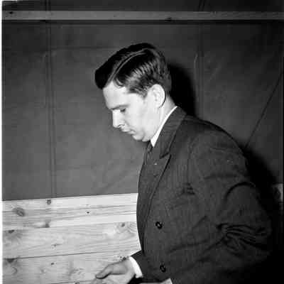 Man in a civilian suit holding a mess kit
