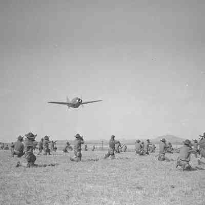 Soldiers aiming their rifles at a low-flying O-47 aircraft
