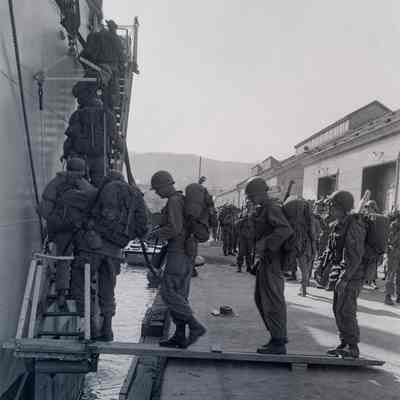 Soldiers in field gear boarding a docked ship