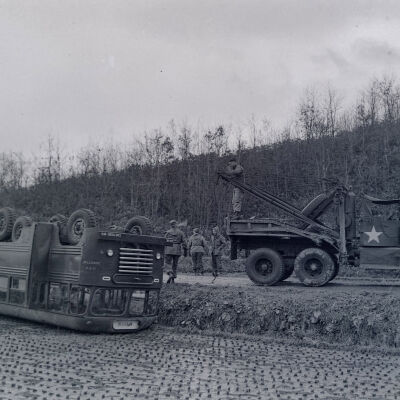 Army wrecker retrieving a wrecked bus