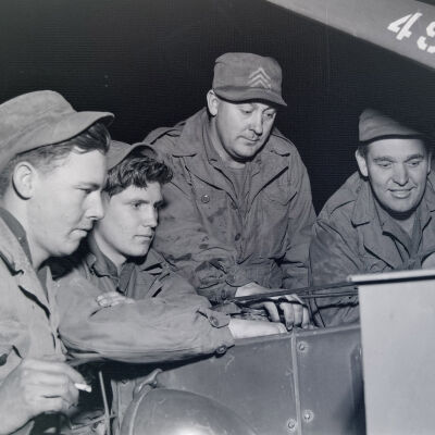 Group of soldiers looking under the hood a truck