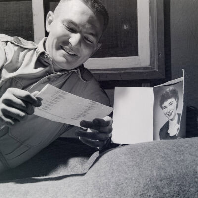 Soldier on bed reading with a picture of a girl
