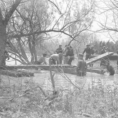 Soldiers constructing a pontoon bridge