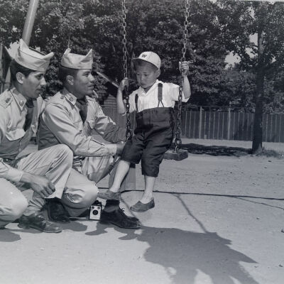 Soldiers talking to a Japanese child on a swing