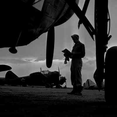 Airman stands in airfield among aircraft