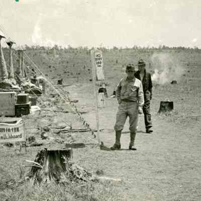 Soldiers standing next to rolled up tents