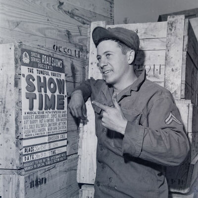 Soldier looking over shipping crates labeled "Show Time"