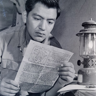 Soldier reading a newsletter by lantern light