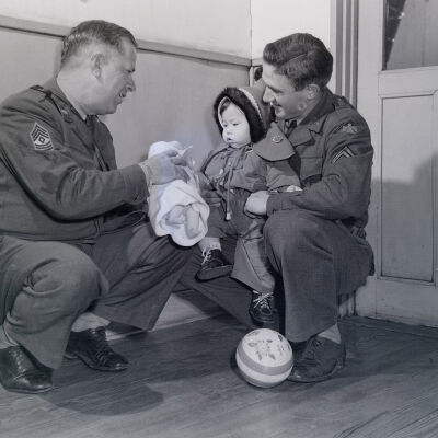 Two soldiers giving toys to a Japanese toddler